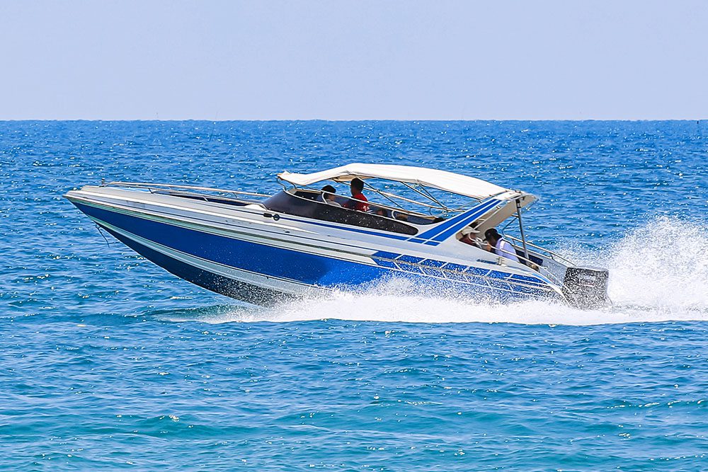 A blue and white speedboat with passengers skims across the open water.